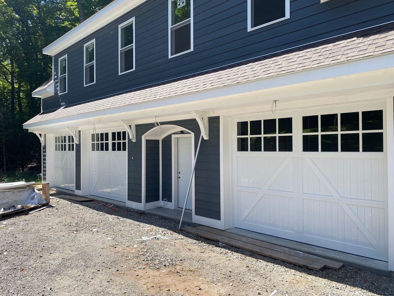 Three-car garage with white doors, gray siding, and a white trim.