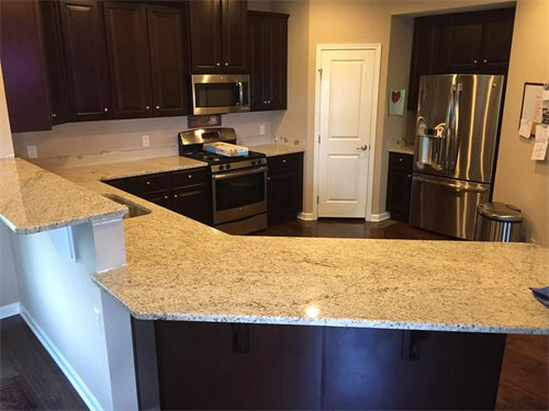 Dark wood kitchen with granite countertops, stainless steel appliances, and a white door.