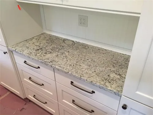 White kitchen cabinets with a granite countertop, and a shelf above.