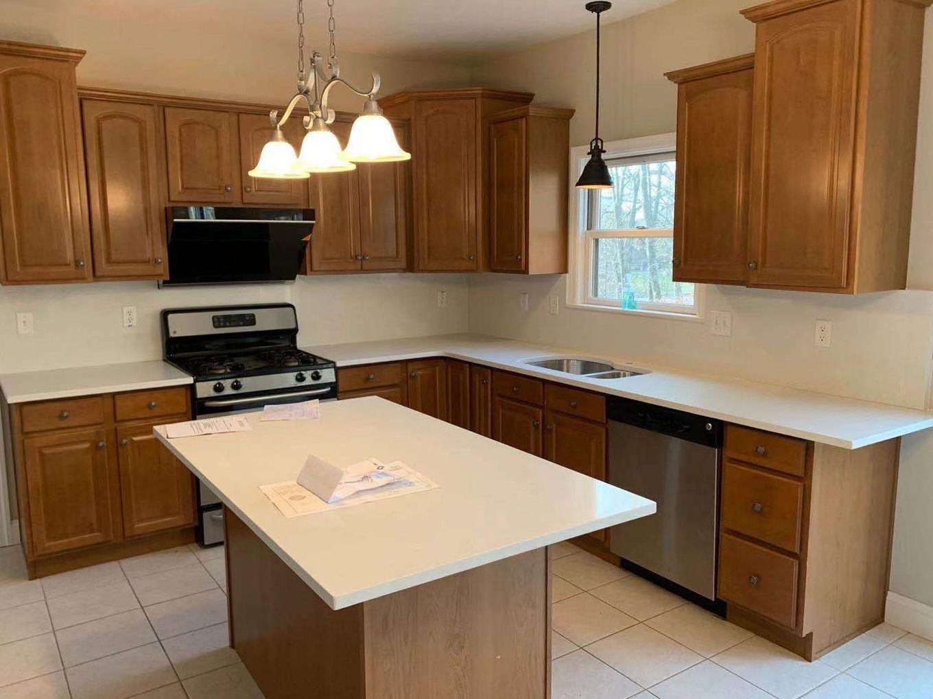 Kitchen with light brown cabinets, white countertops, stainless steel appliances, and a center island.