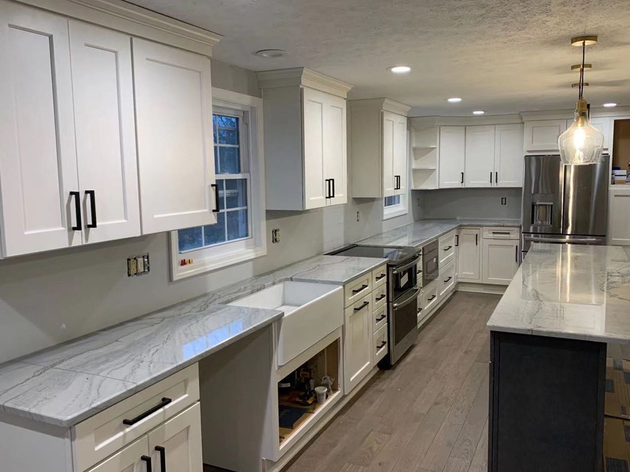 White kitchen with gray countertops, stainless steel appliances, and a dark gray island.