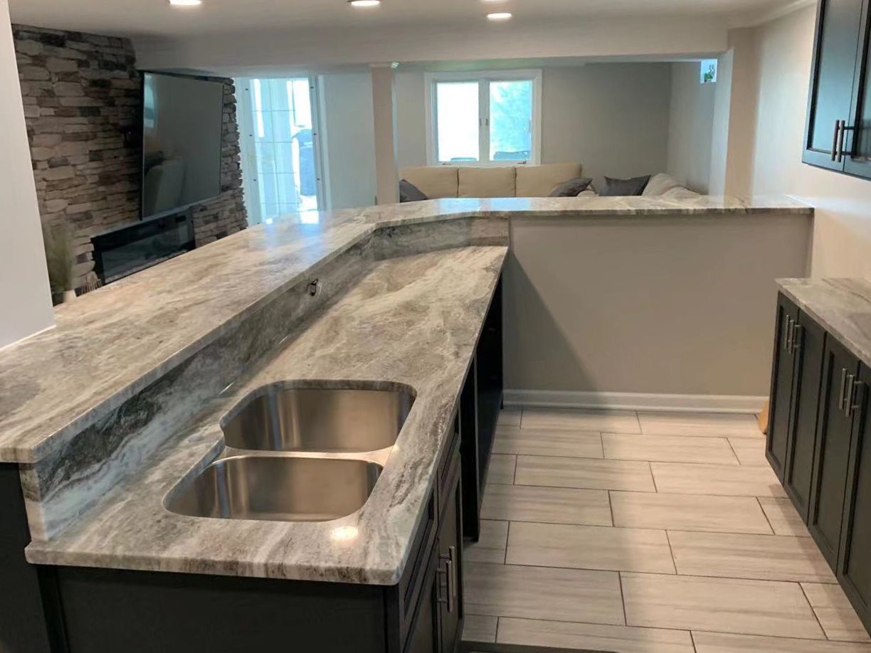L-shaped kitchen bar with gray countertop and stainless steel sink; cabinets below.