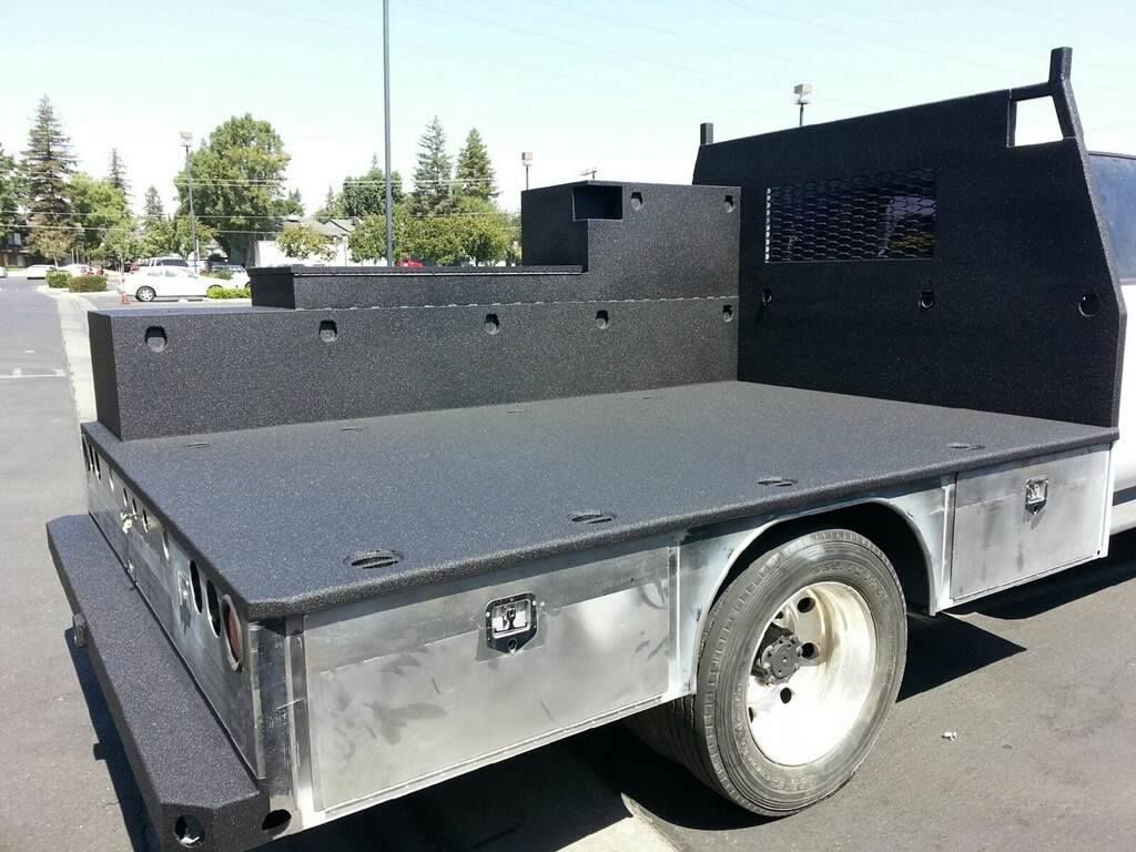 A silver truck with a black bed is parked in a parking lot