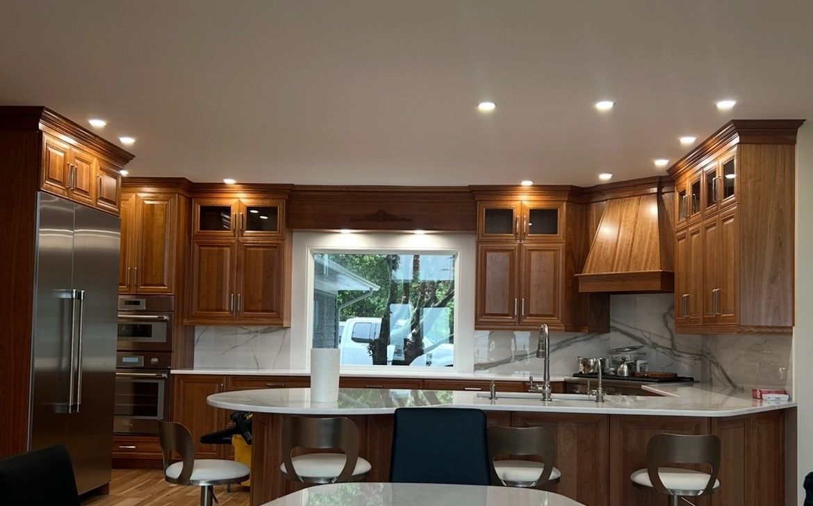 A kitchen with wooden cabinets , stainless steel appliances , a table and chairs.