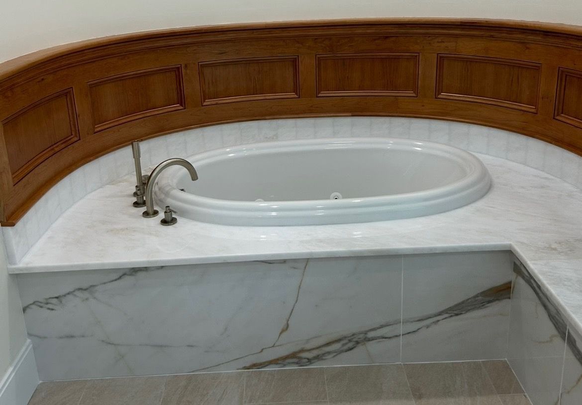 A bathtub is sitting on top of a marble counter in a bathroom.