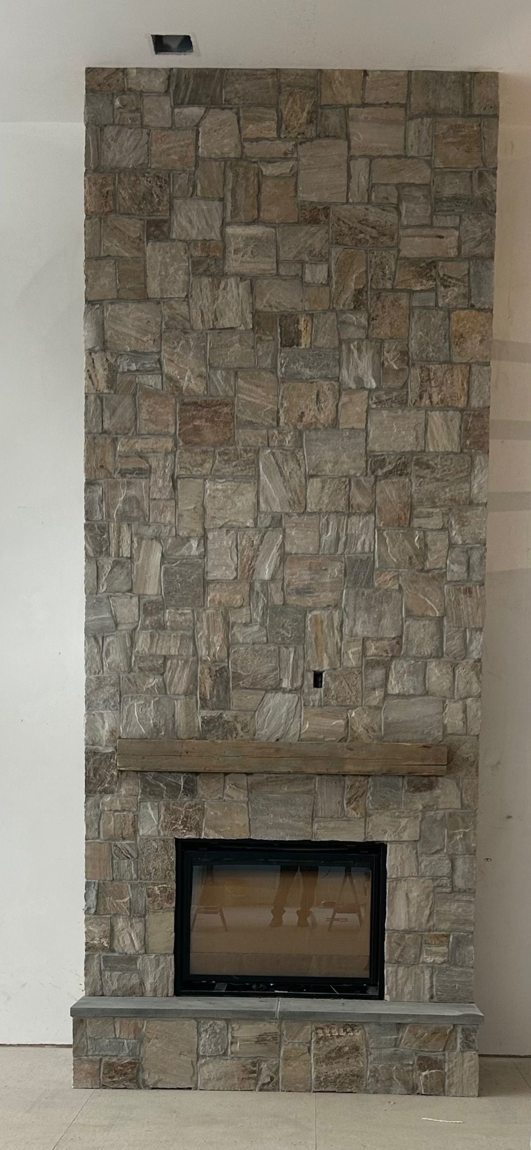 A stone fireplace with a mantle in a living room.