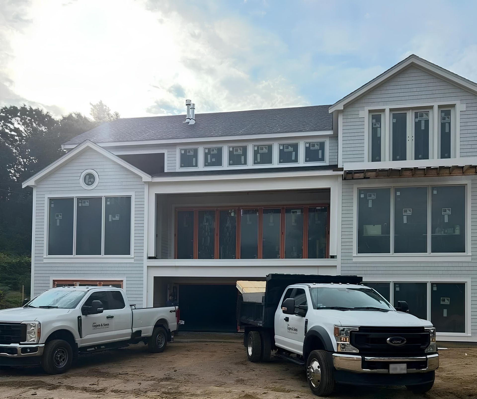 Two trucks are parked in front of a large white house.