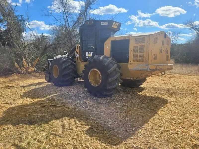 Yellow CAT forestry machine in a wooded area, preparing the ground.