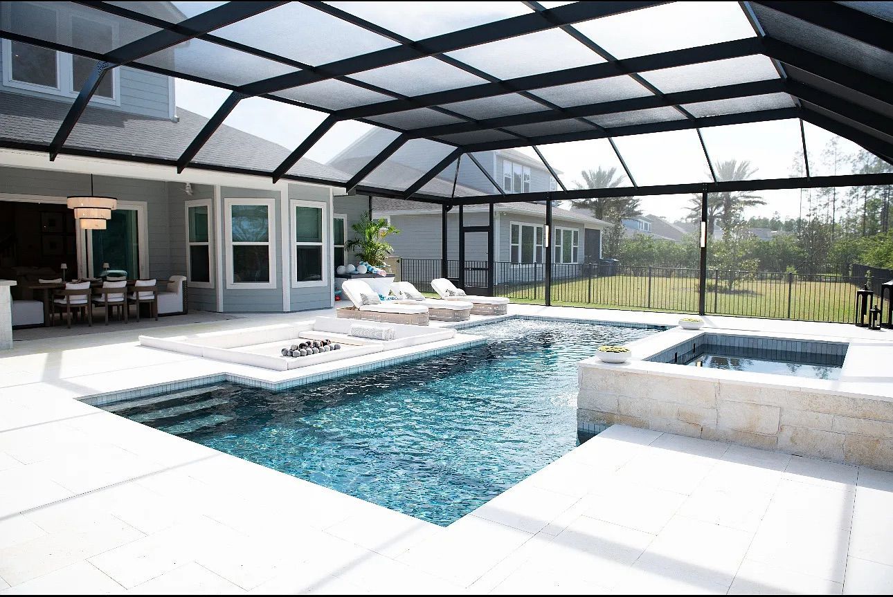 A luxury outdoor pool area with a screened enclosure. It features a pool, hot tub, lounge chairs, and a dining area.