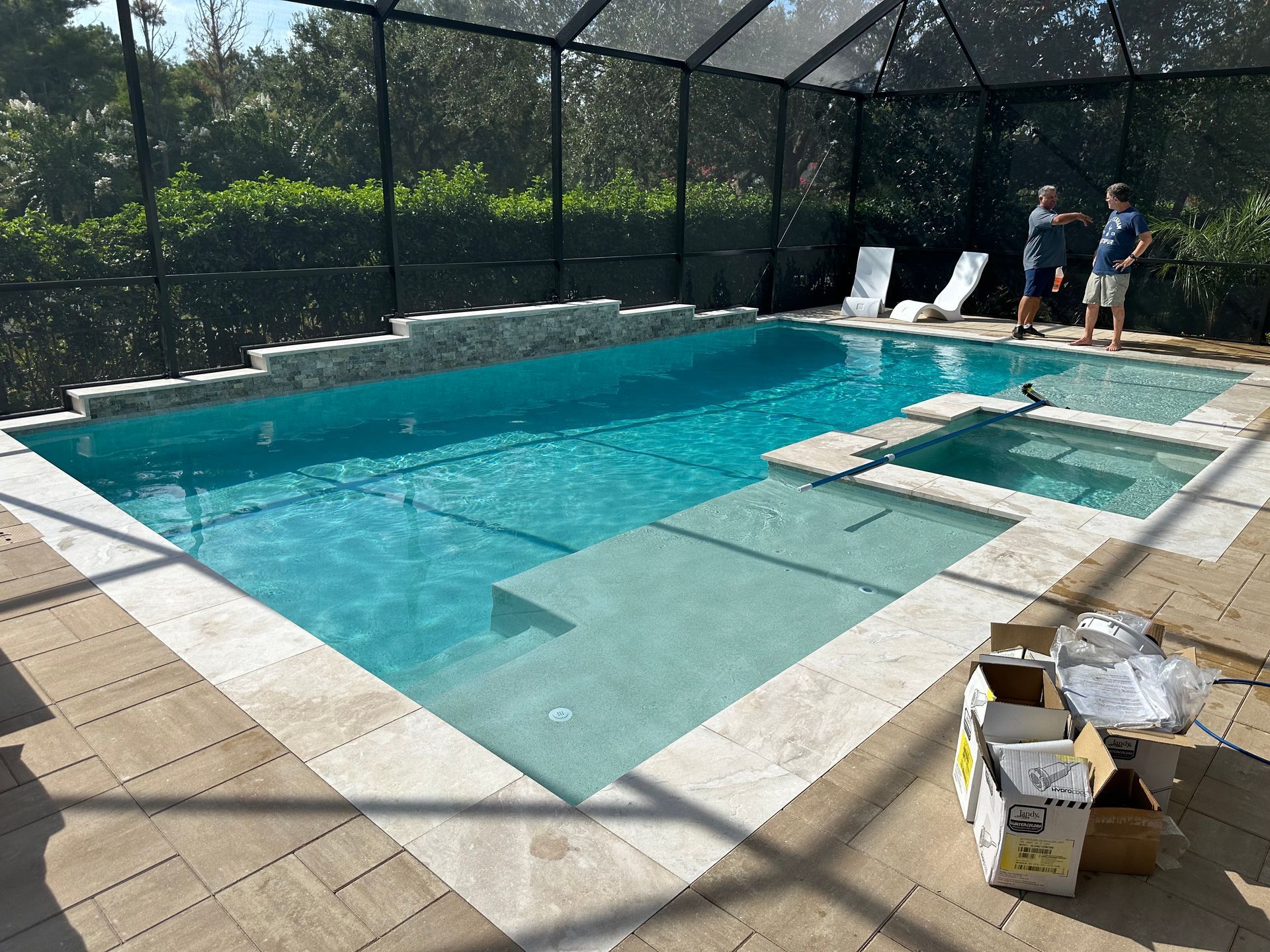 A newly constructed swimming pool and spa in a backyard setting, with two men standing nearby.