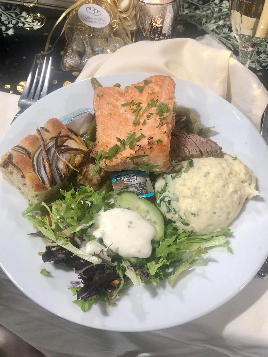Plate of food with salmon, bread, salad, mashed potatoes, and sauce.
