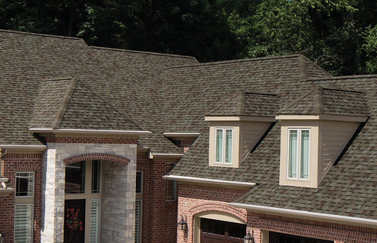 A brick house with a brown roof and two windows