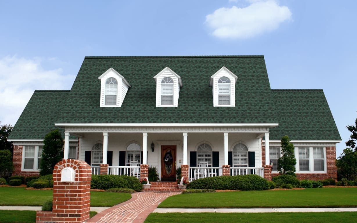 A large house with a green roof and white trim