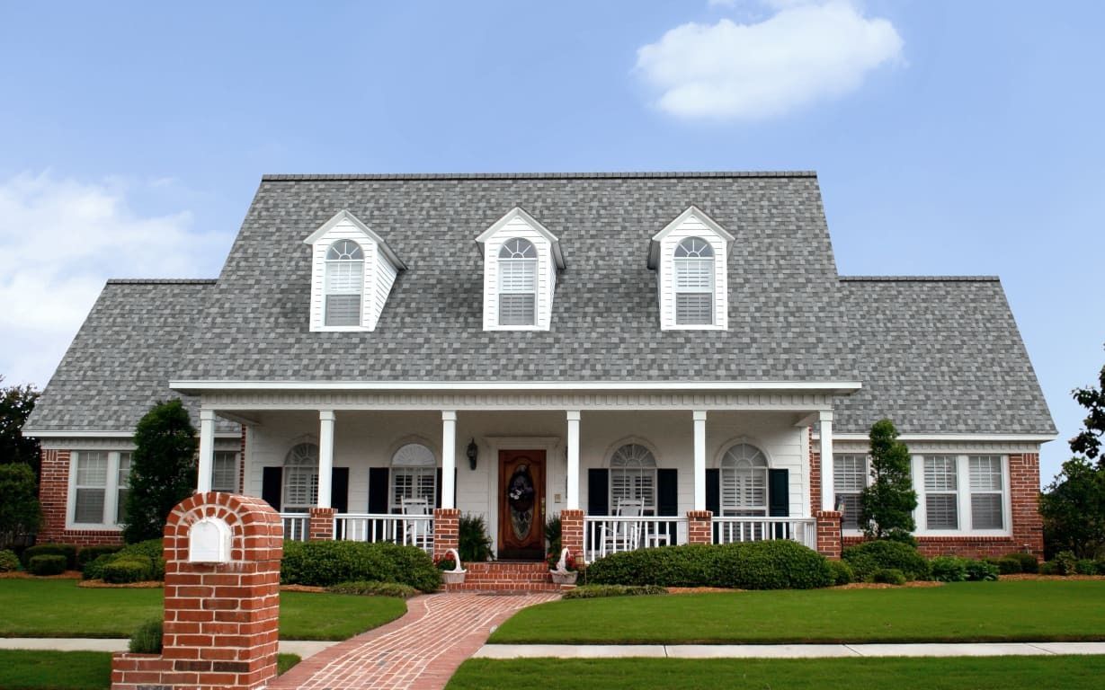 A large white house with a gray roof and three windows