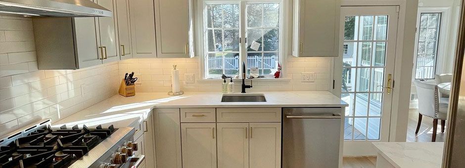 a kitchen with white cabinets, a stove, a sink, and a window