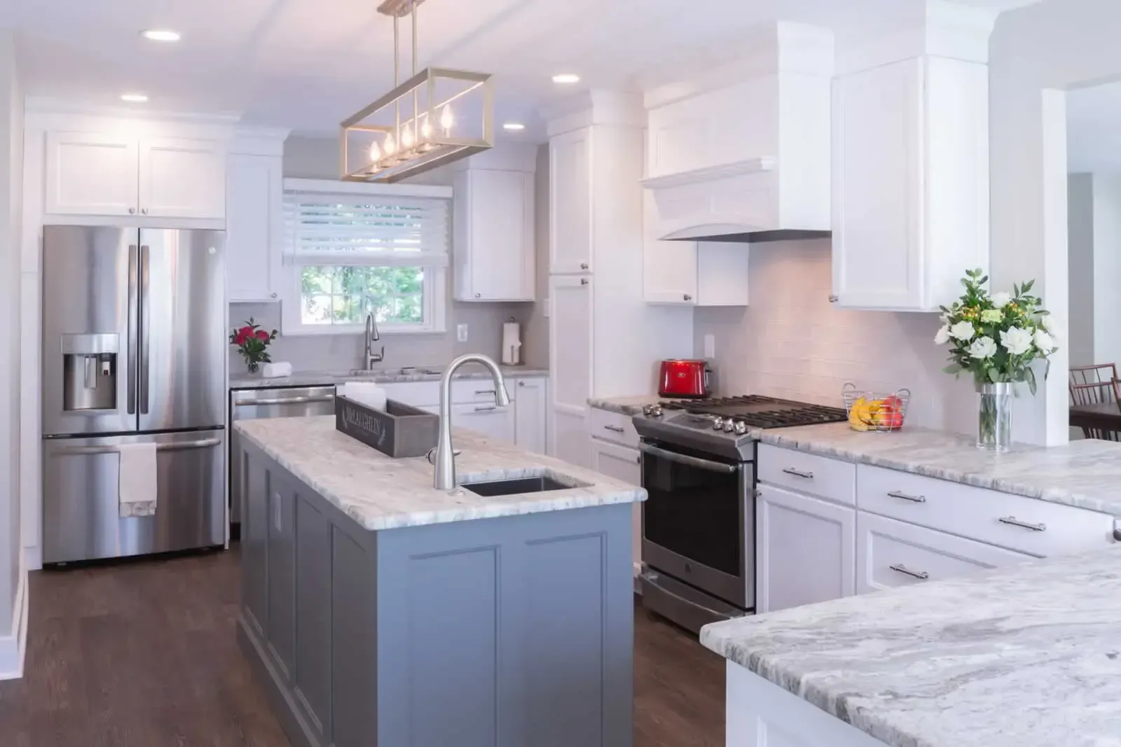 A kitchen with white cabinets , stainless steel appliances , granite counter tops and a large island.