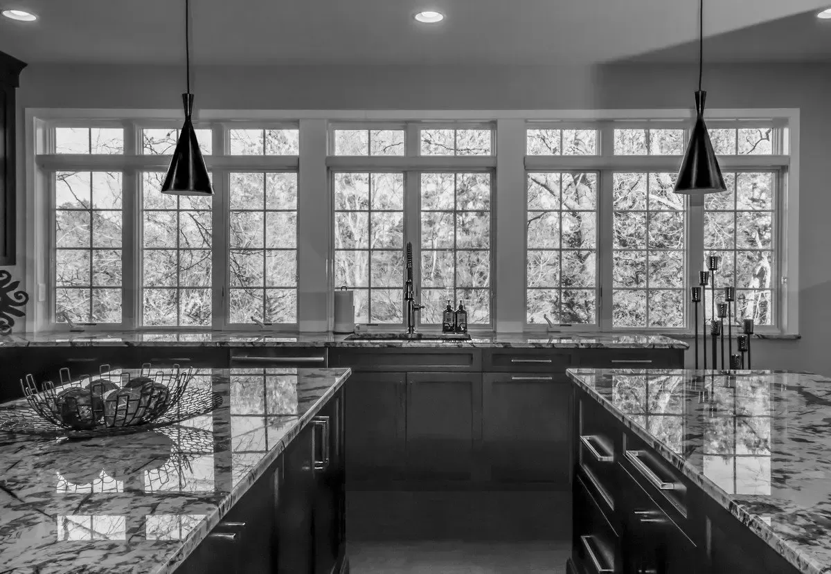 A black and white photo of a kitchen with a lot of windows.