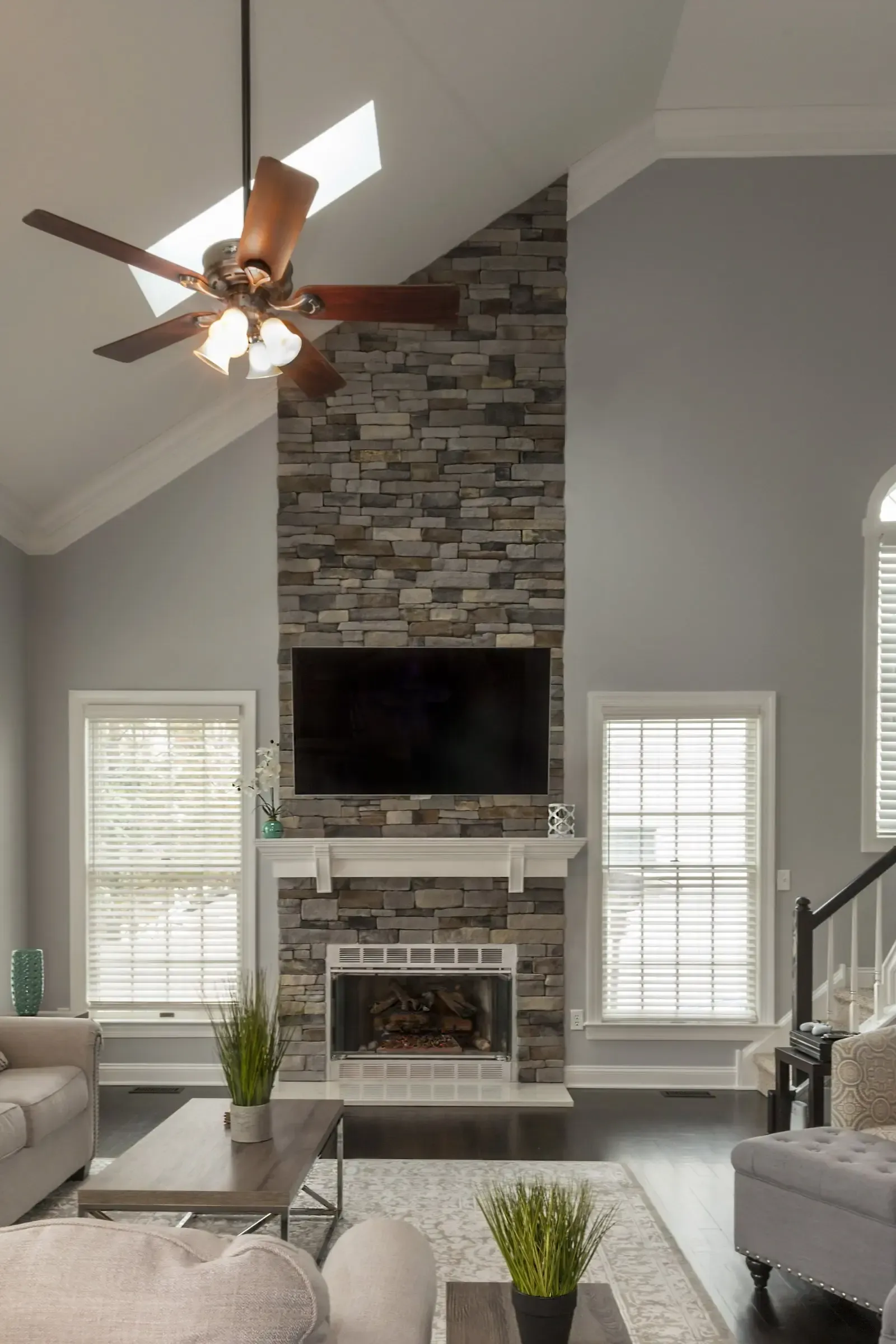 A living room with a fireplace , television and ceiling fan.