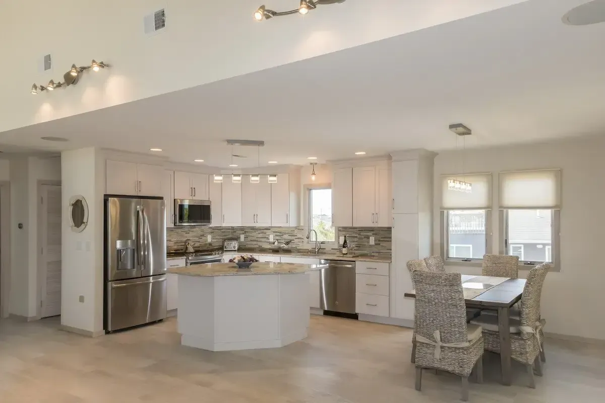 A kitchen and dining room in a house with white cabinets and stainless steel appliances.
