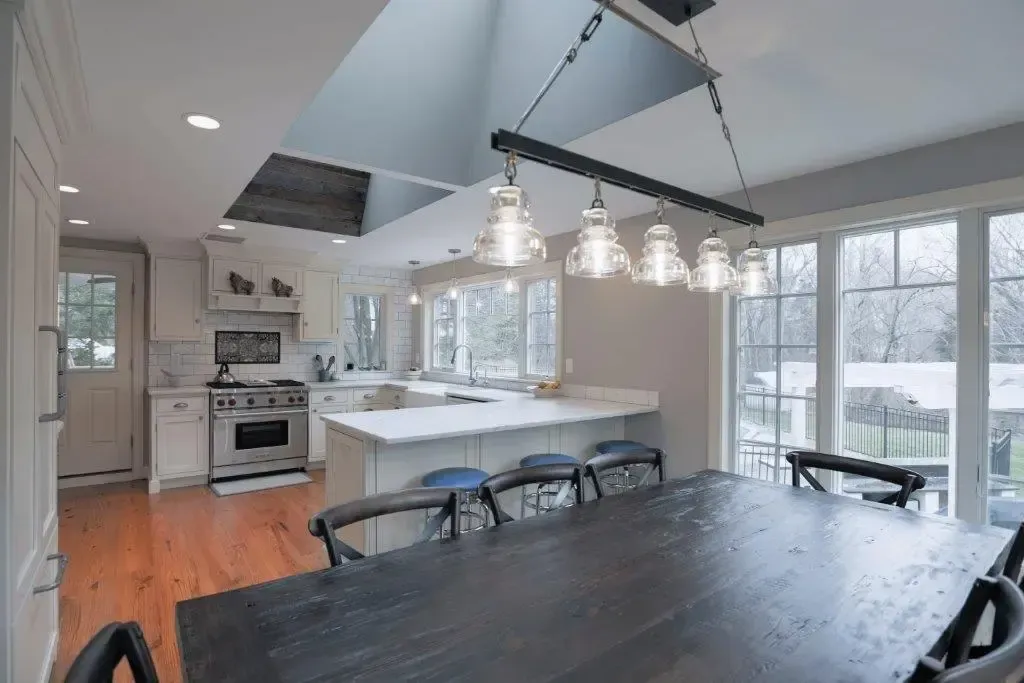 A dining room table in a kitchen with a chandelier hanging from the ceiling.