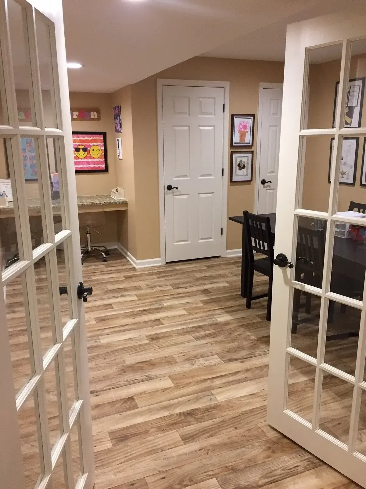 A room with hardwood floors and french doors leading to a dining room.