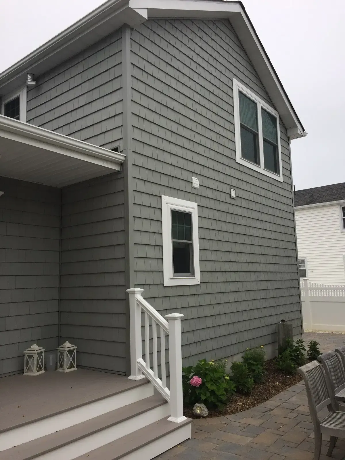 A gray house with a white railing and stairs