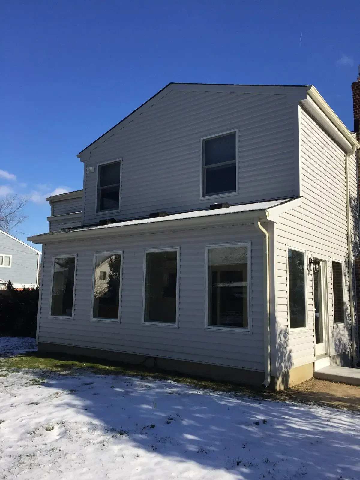 A white house with a lot of windows is sitting in the snow.
