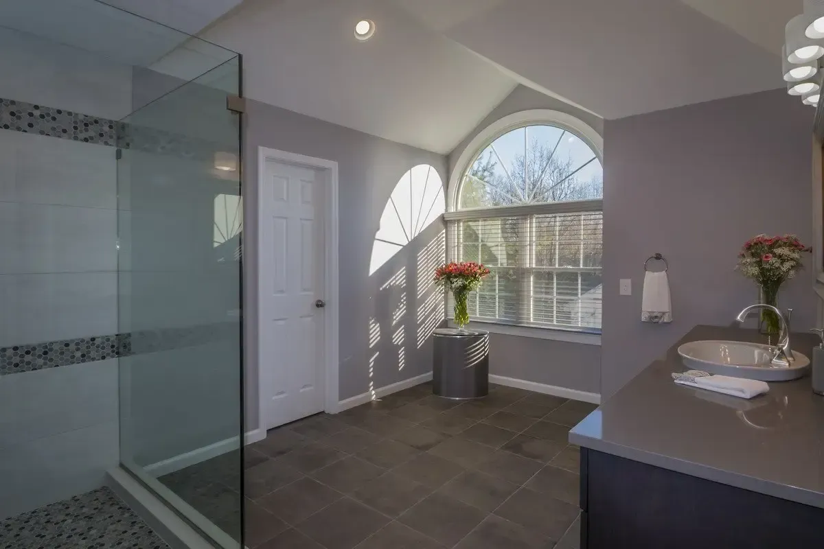 A bathroom with a walk in shower and a sink