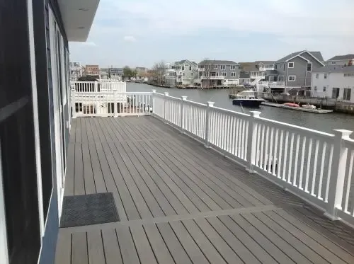 A large deck with a white railing overlooking a body of water