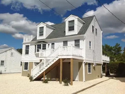 A white house with stairs leading up to the second floor