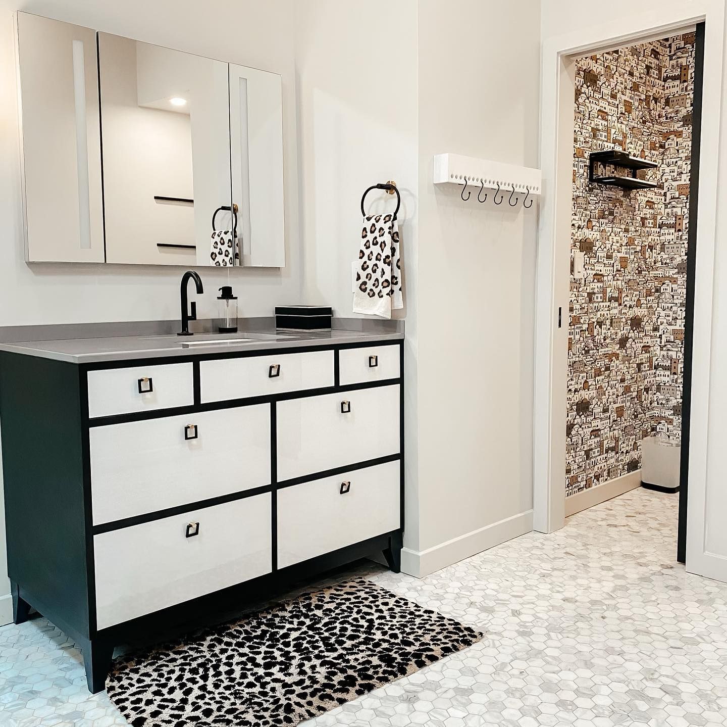 A bathroom with a black and white vanity and a leopard print rug