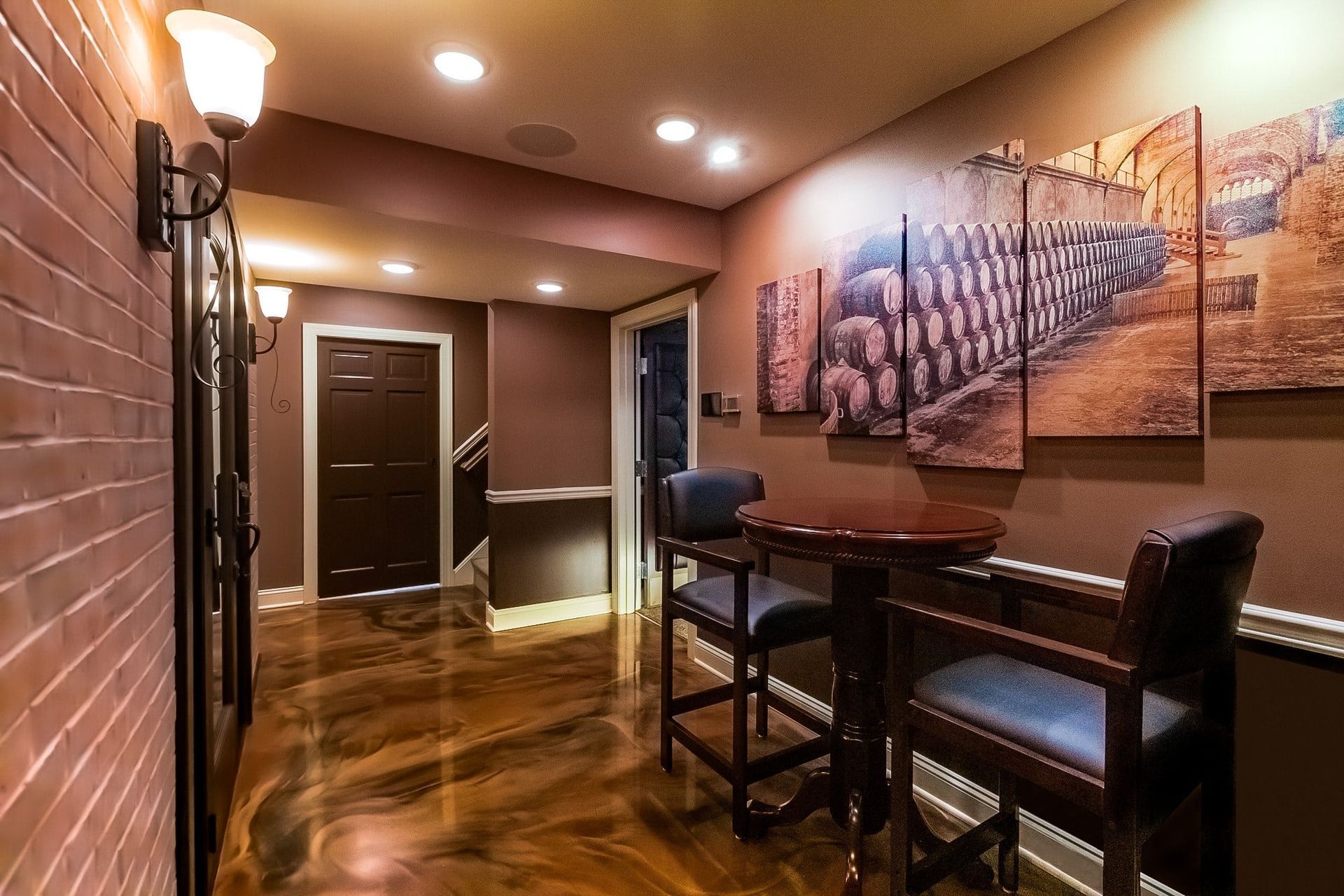 A hallway with a table and chairs and a painting on the wall.