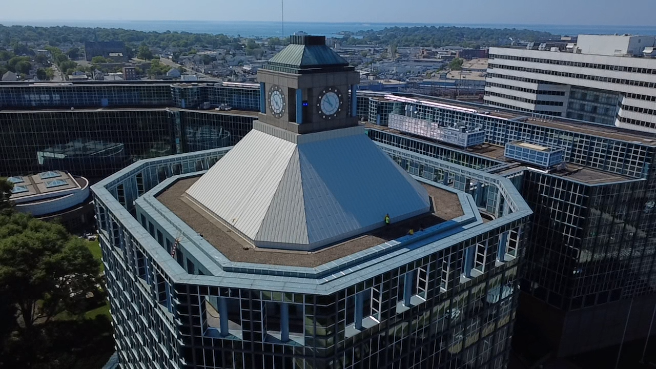 Aerial view of a modern glass building with a white pyramidal roof and clock tower