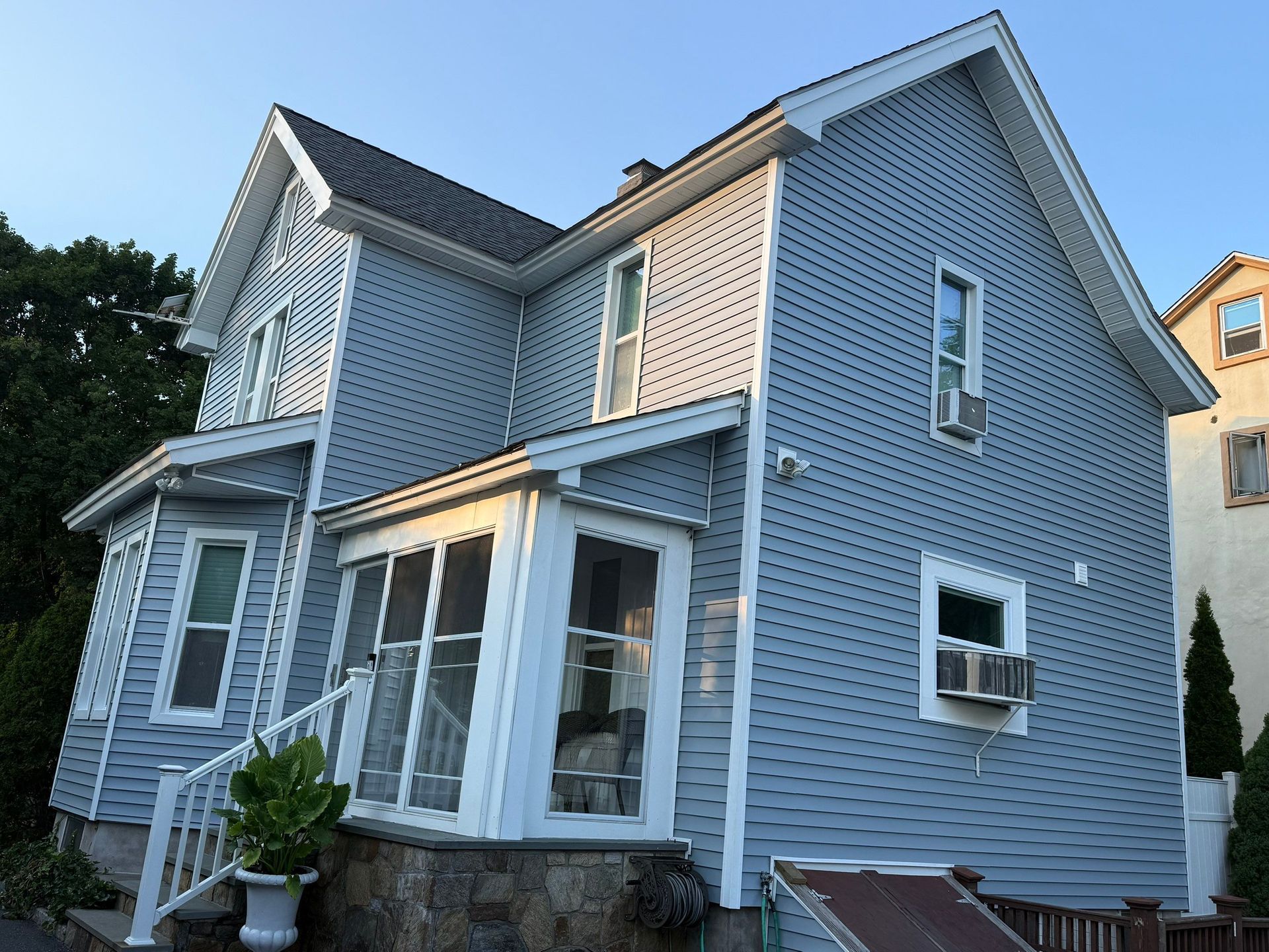 Blue two-story house with white trim and front porch at dusk