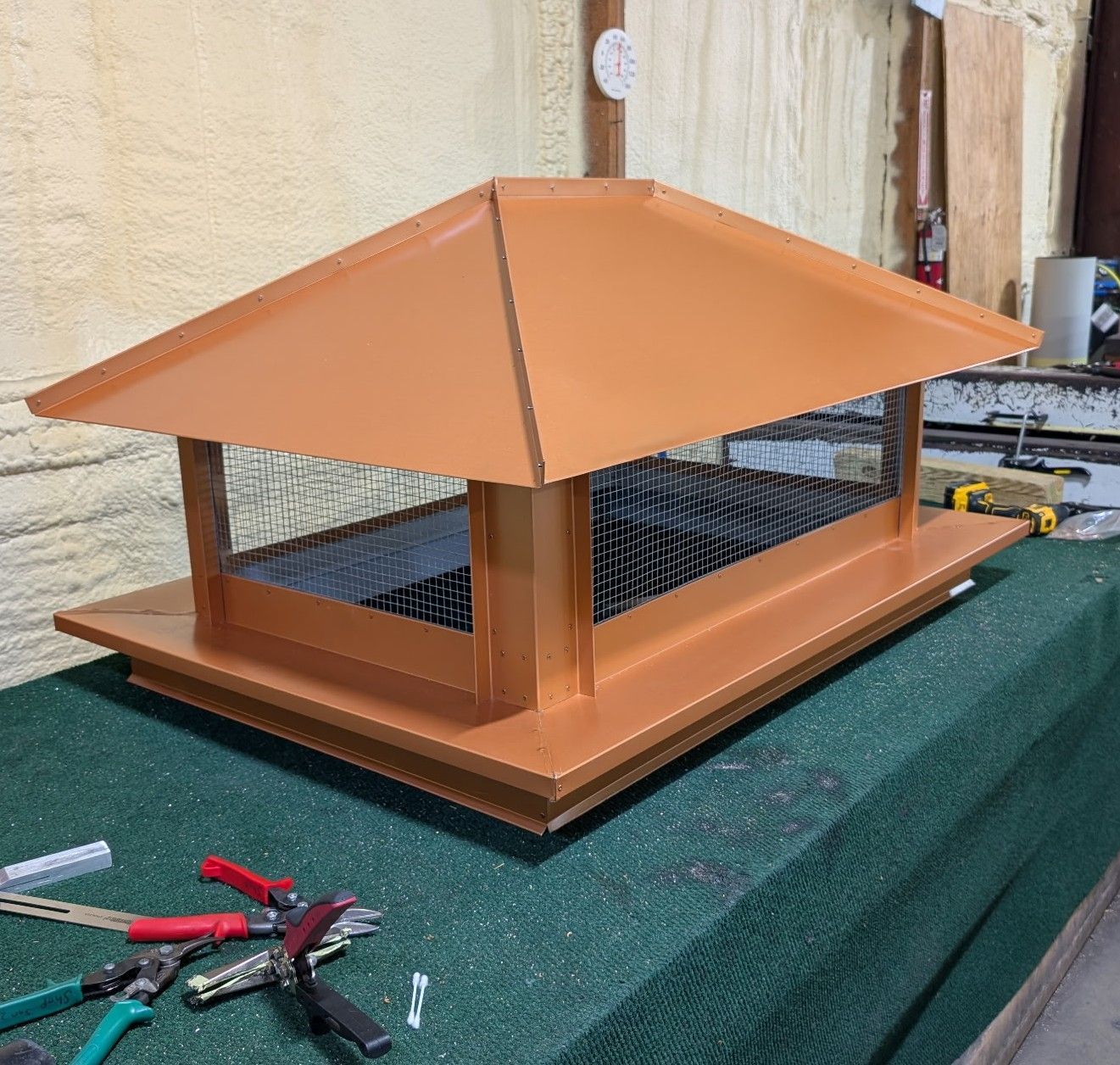 Orange-roofed wooden model structure on a workbench, with tools nearby