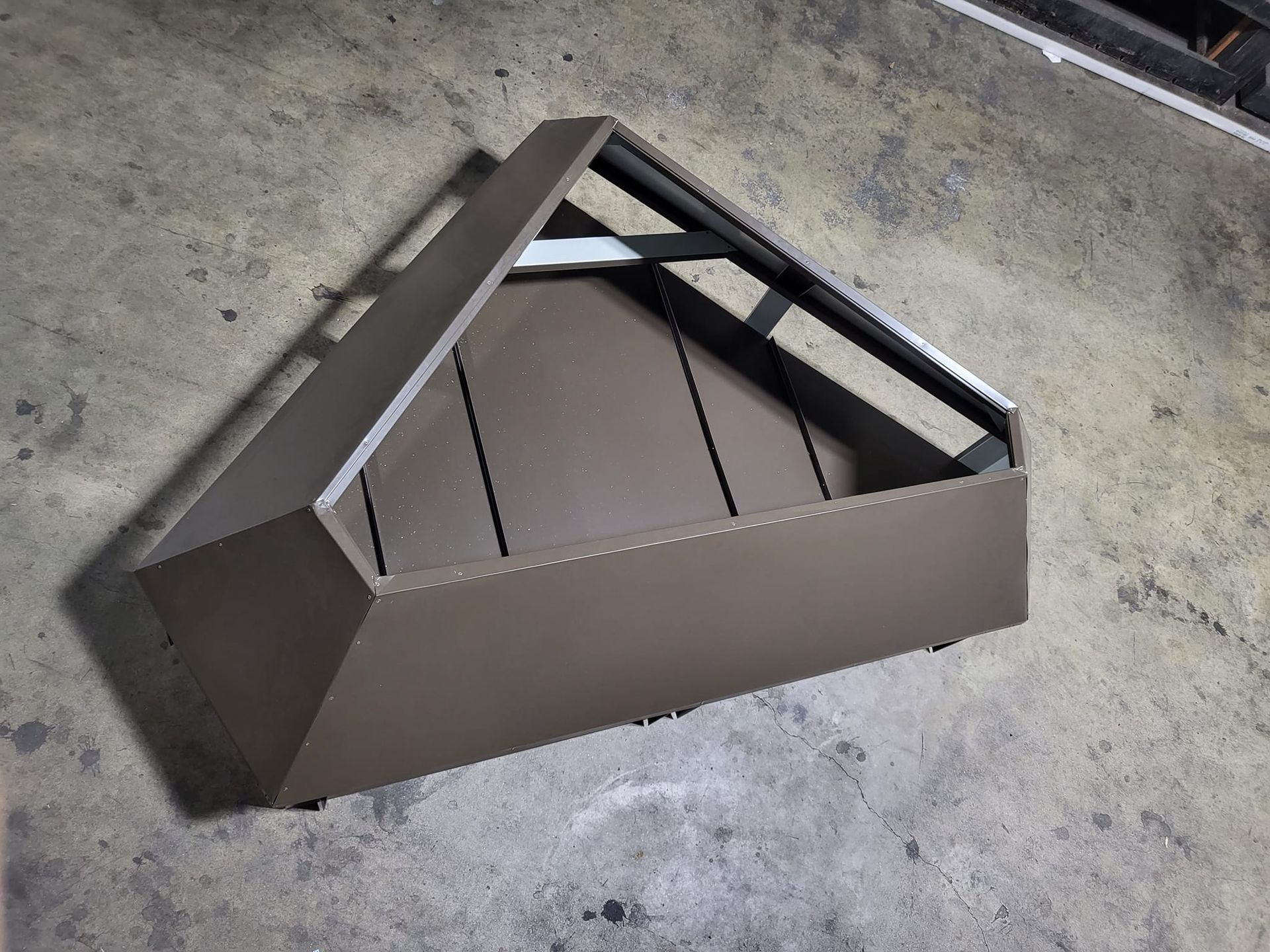 A triangle shaped box is sitting on a concrete floor