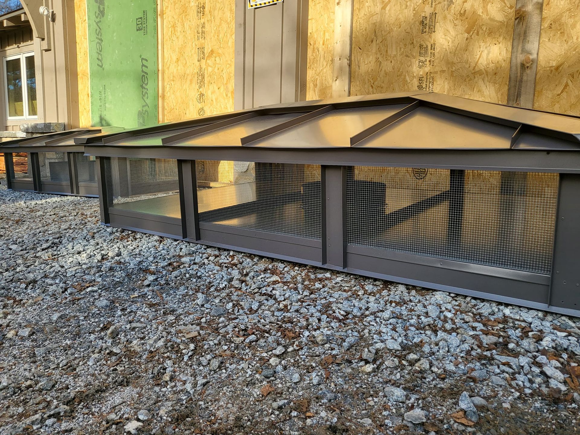 A metal structure is sitting on top of a pile of gravel in front of a building.