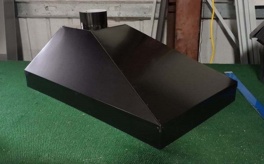 A black hood is sitting on top of a green carpet.