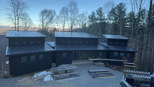 A large black house is being built in the middle of a forest.