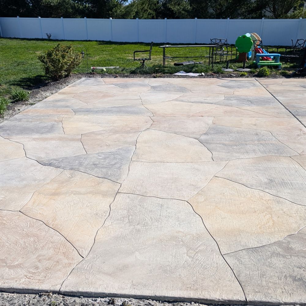 Cracked concrete patio with a bench, green lawn, and children’s playset in the background