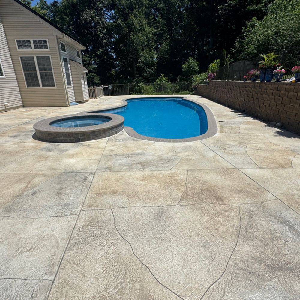 Backyard pool with attached hot tub and concrete patio beside a house