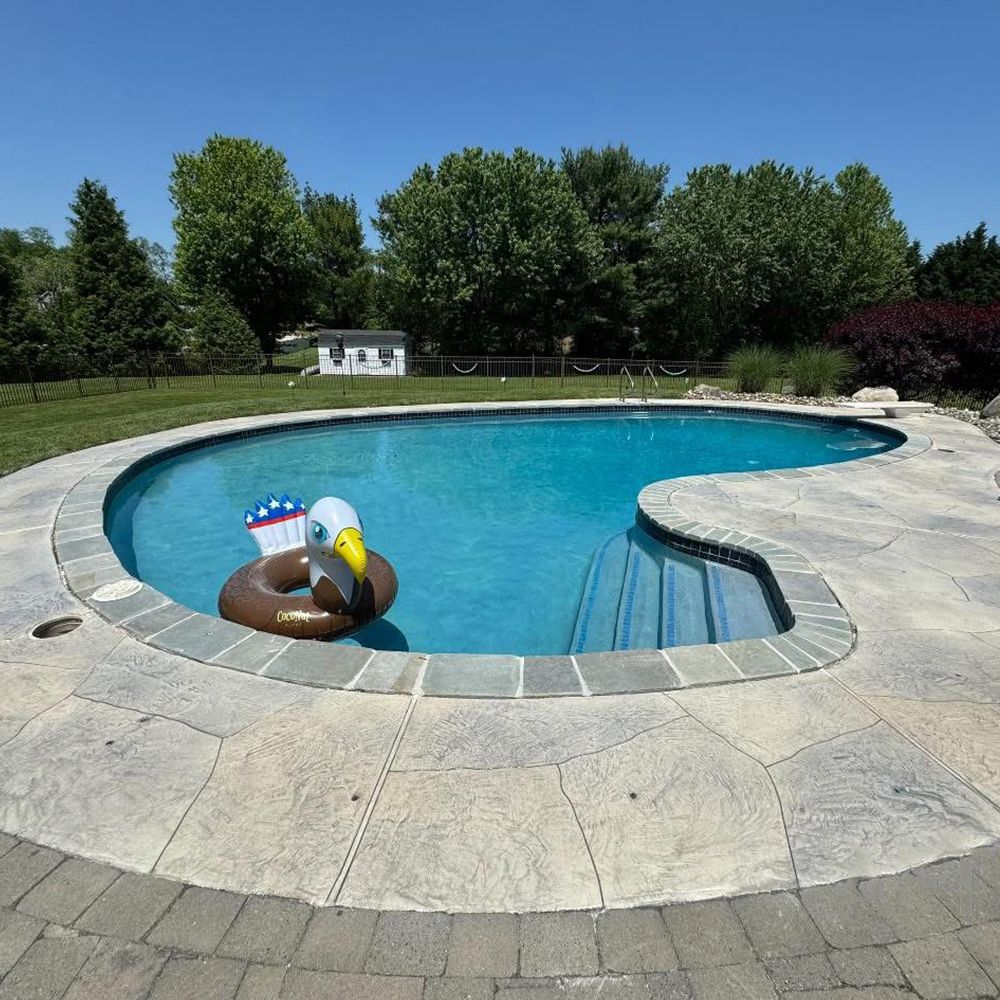Backyard swimming pool with a brown-and-white inflatable flamingo float on the water.