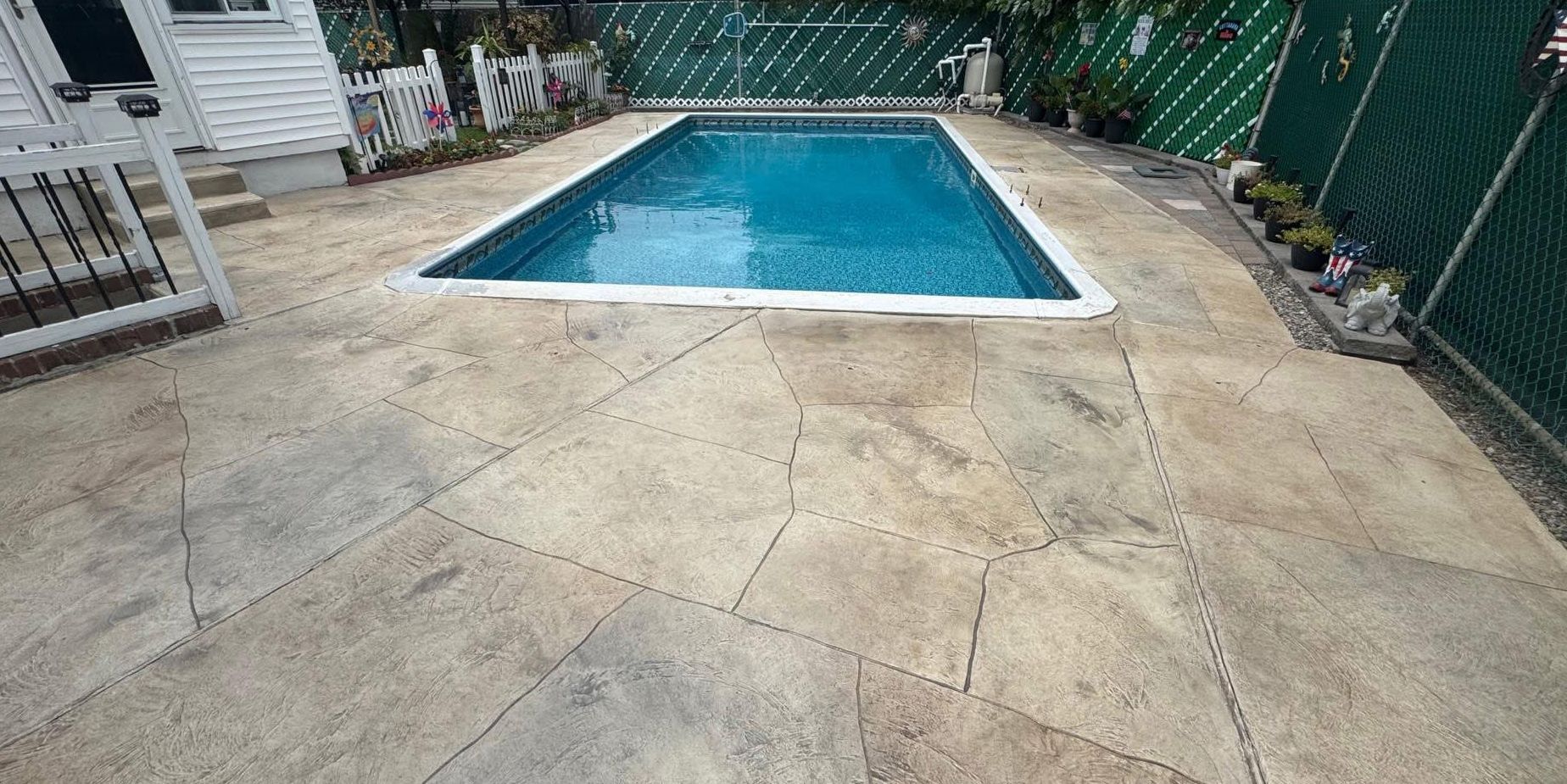 Backyard patio with a blue swimming pool and concrete deck
