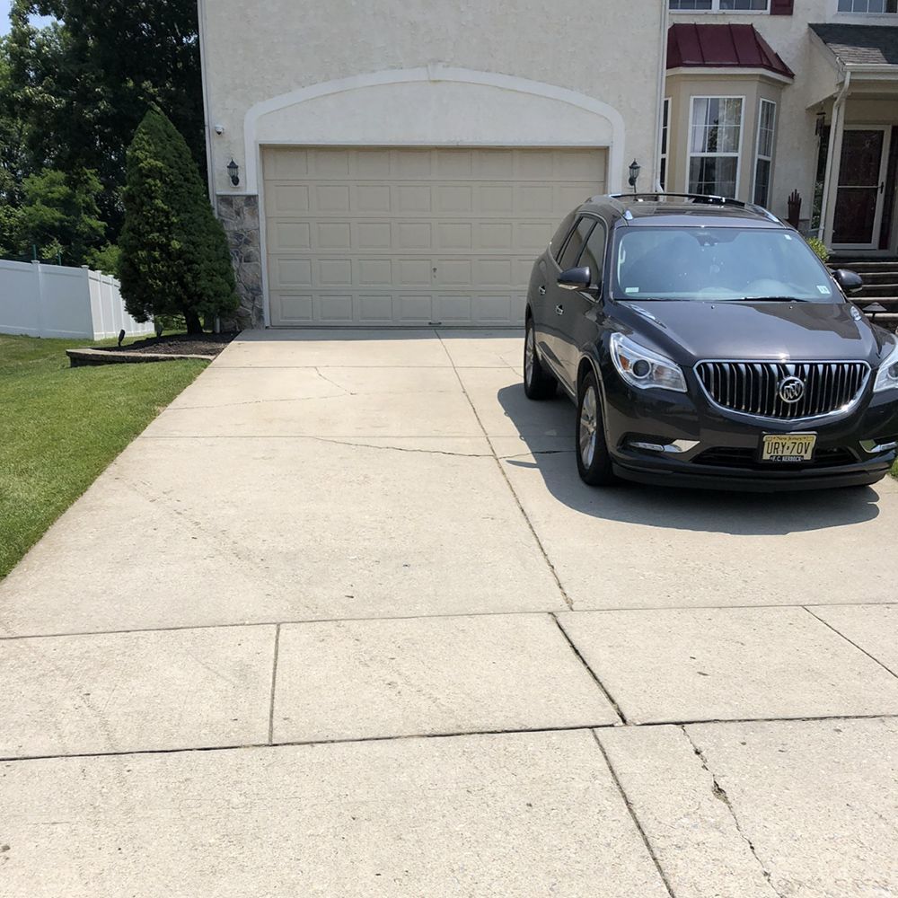 Driveway leading to a beige garage with a black SUV parked on the right side.