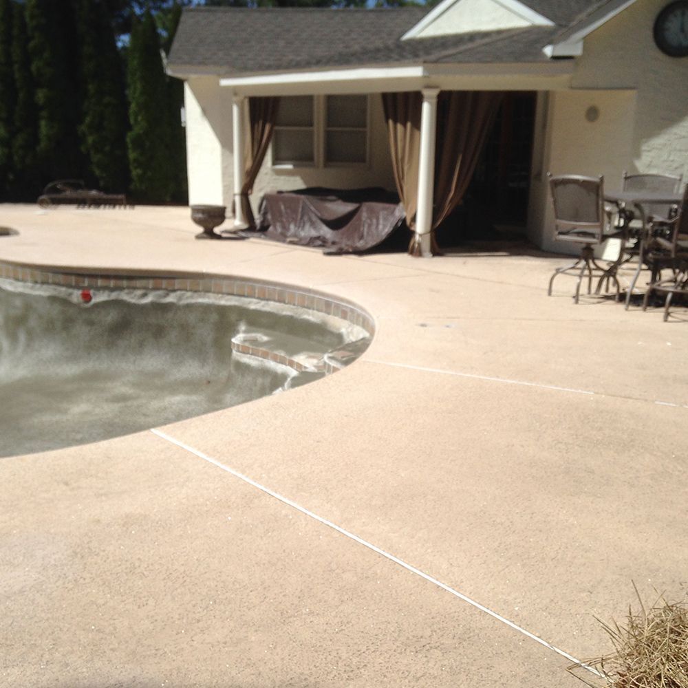 Backyard patio with a swimming pool and covered outdoor seating area in bright sunlight