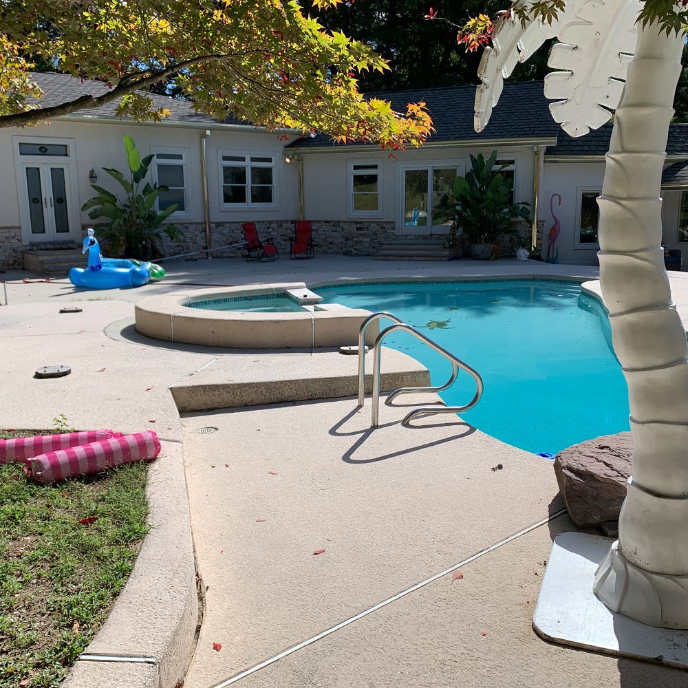 Backyard swimming pool with curved steps, lounge float, and white house in the background