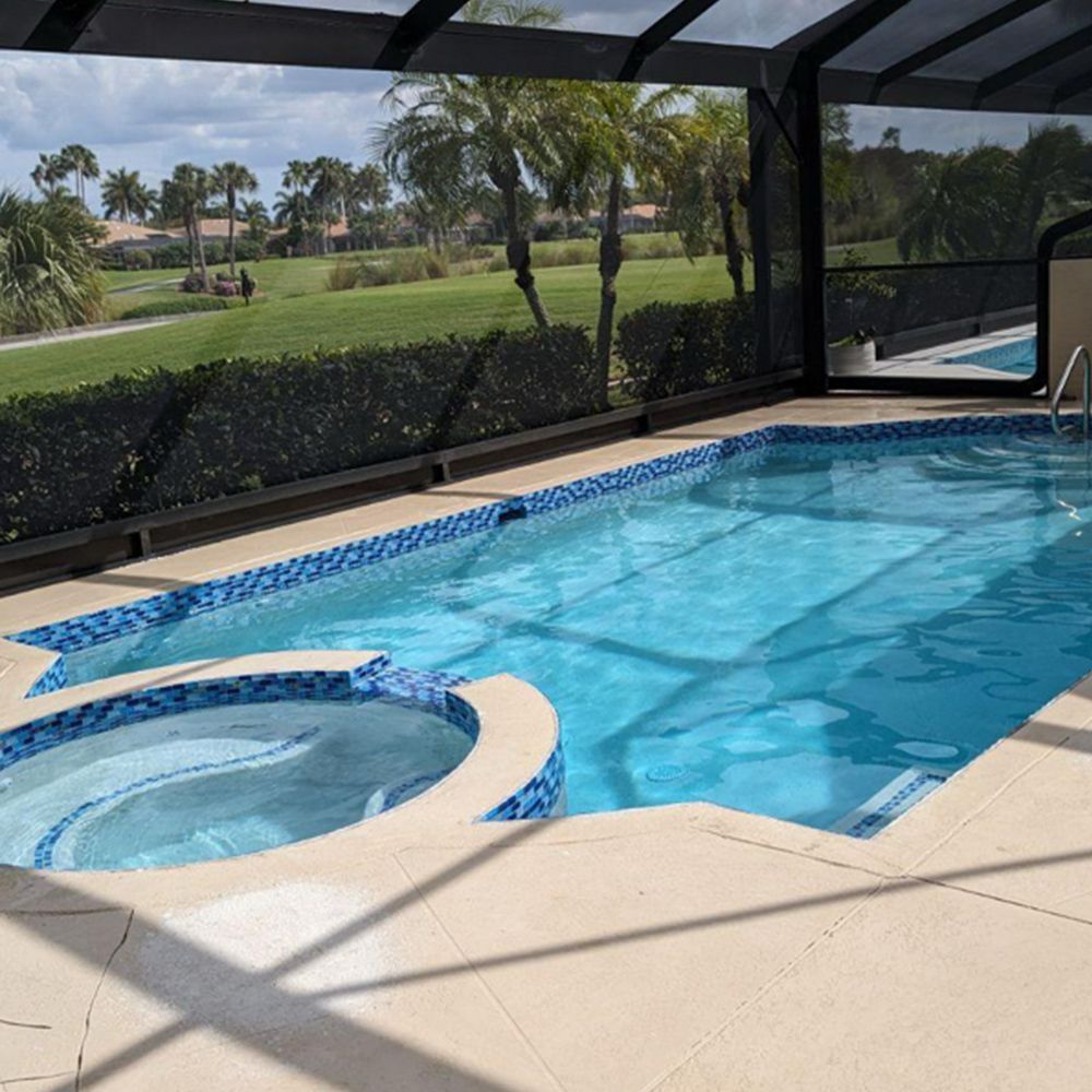 Screened backyard pool with attached spa, blue water, and view of a golf course beyond the patio.