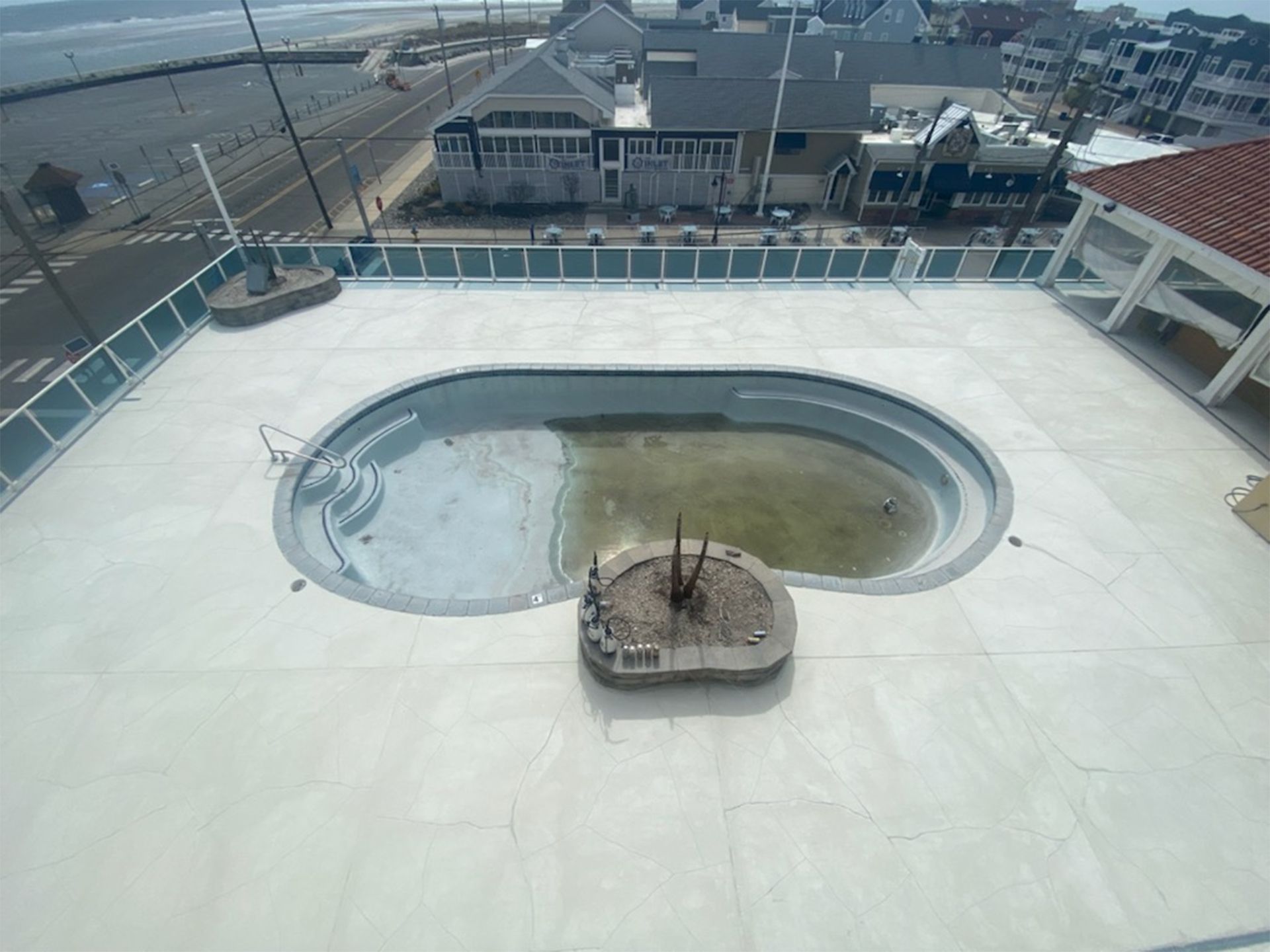 Rooftop pool with shallow water, overlooking buildings and the beach in the distance