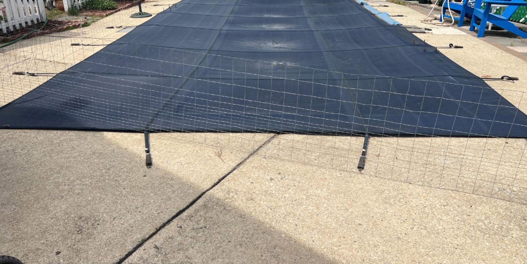 Black solar panel array covering a paved outdoor area, with metal supports visible underneath