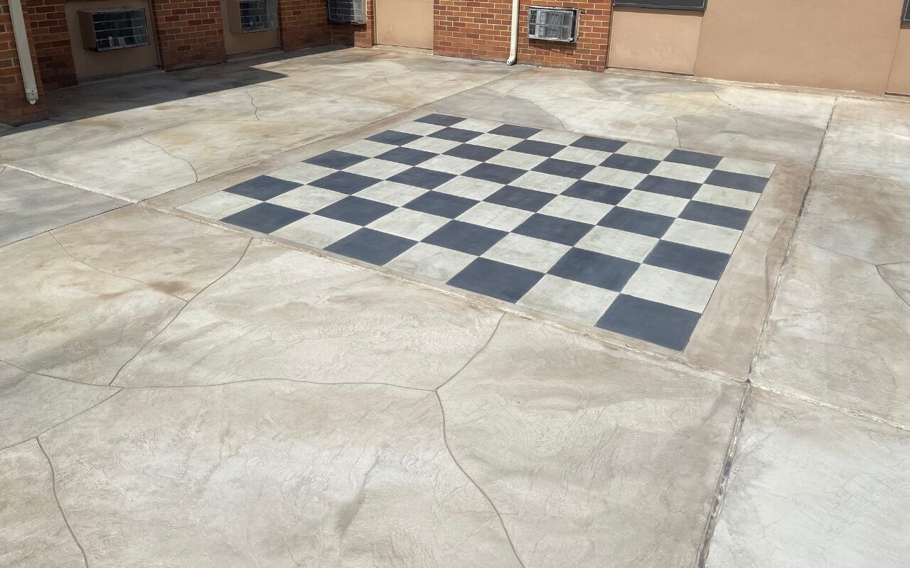 Outdoor courtyard with a large black-and-white checkerboard pattern painted on the ground